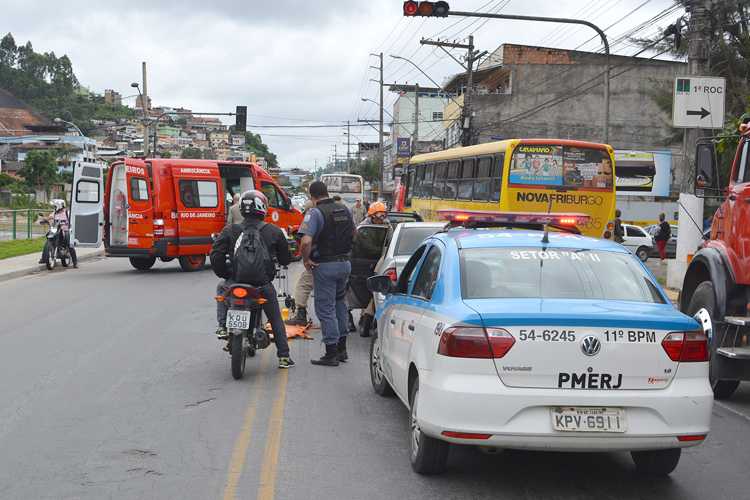 à esquerda, o atendimento do operário, à direita, os carros envolvidos no acidente de trânsito (Foto: Henrique Pinheiro)