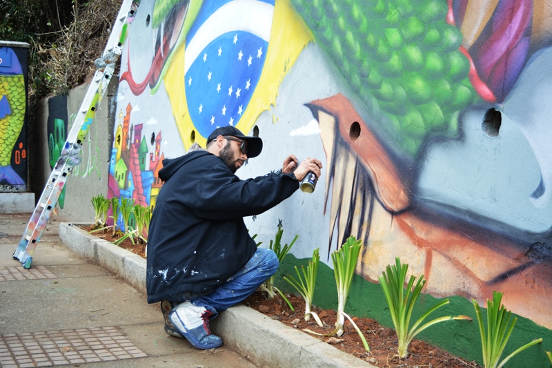Um grafiteiro trabalha na obra, apesar do mau tempo (Foto: Leo Arturius)