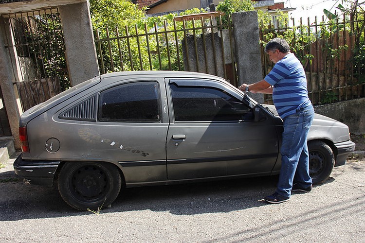 Fiscal cola adesivo num carro abandonado (Foto: João Luccas Oliveira)