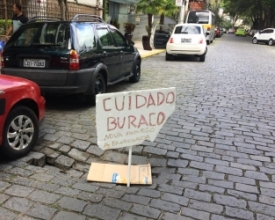 Pista afunda em rua do Centro e cartaz sinaliza “abandono”